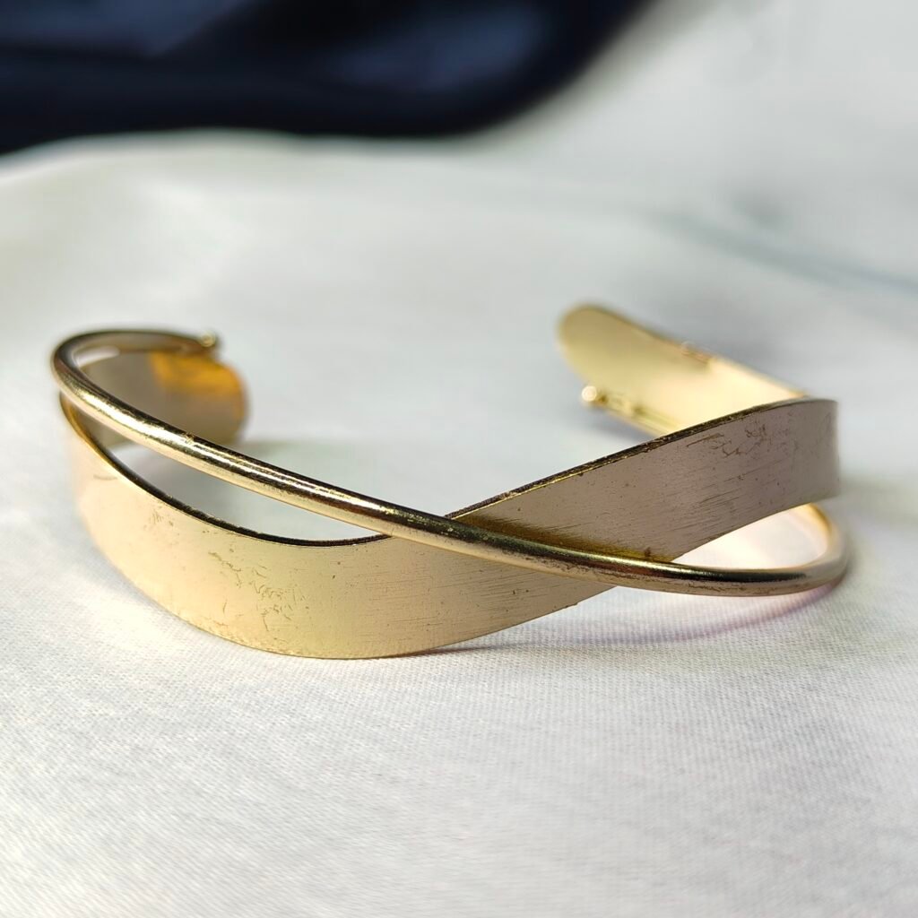 Product Type: Cuff Bracelet Material: Alloy with Gold-Tone Finish Design: Twisted overlapping bands Closure Type: Open adjustable cuff Color: Gold Size: Free size – fits most wrists Occasion: Casual, Party, Festive, Everyday Wear, Gifting Care Instructions: Keep away from water, perfumes, and chemicals; store in a dry jewelry box.